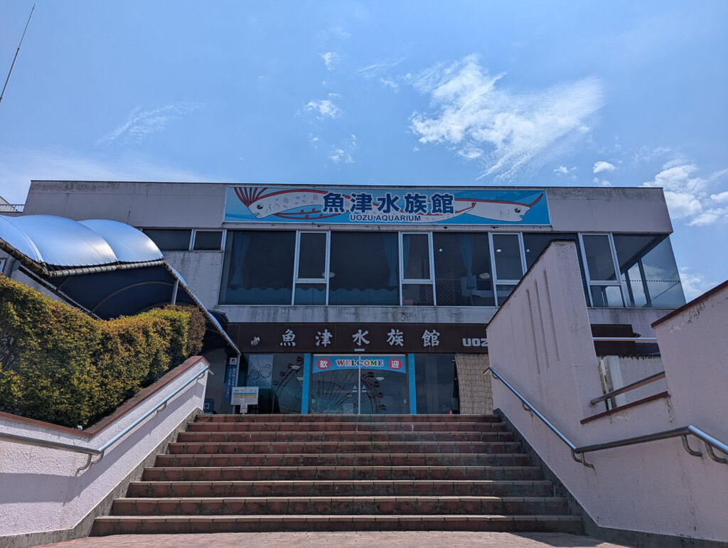 青空の下に建つ魚津水族館の正面入口。階段を上がると看板が見える。