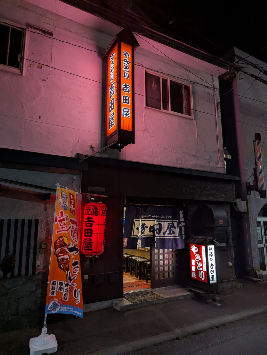 室蘭やきとりの老舗「吉田屋」の夜の店構え。赤提灯と暖簾が灯り、昭和の香りが漂う。