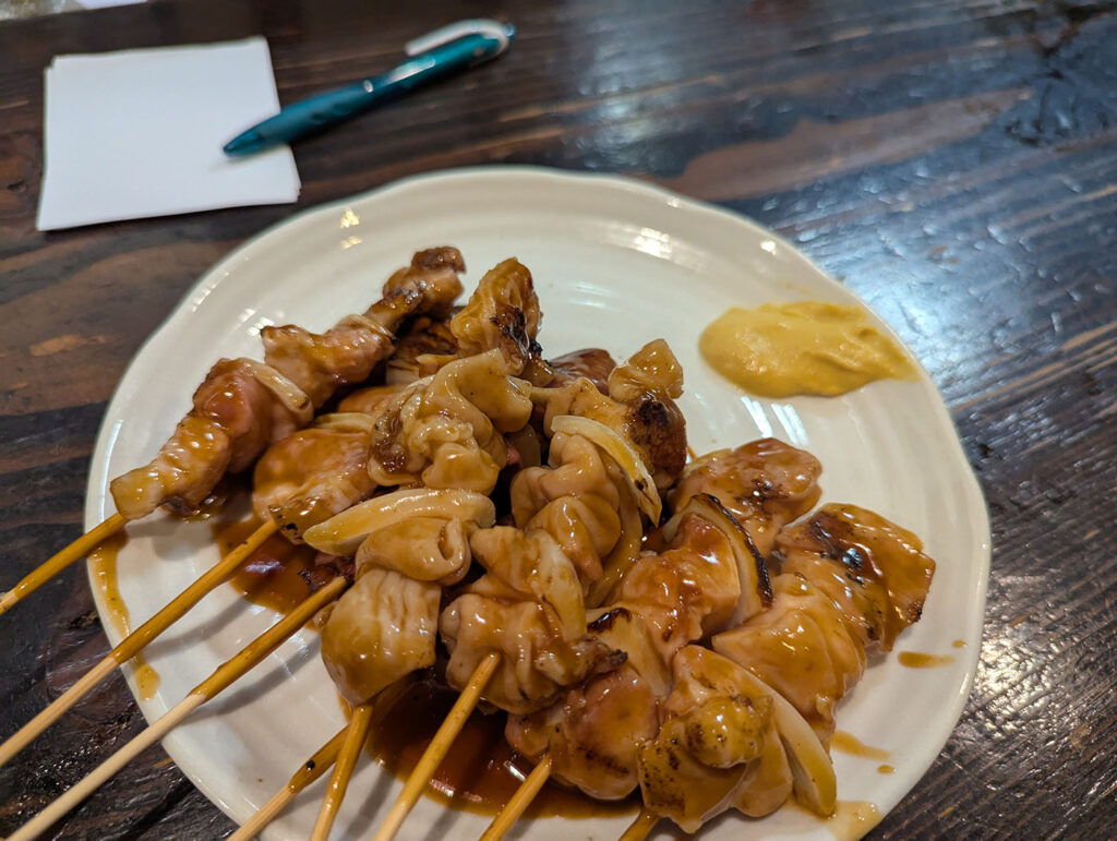 室蘭やきとりの豚肉と玉ねぎの串。甘辛いタレと洋がらしが添えられている。