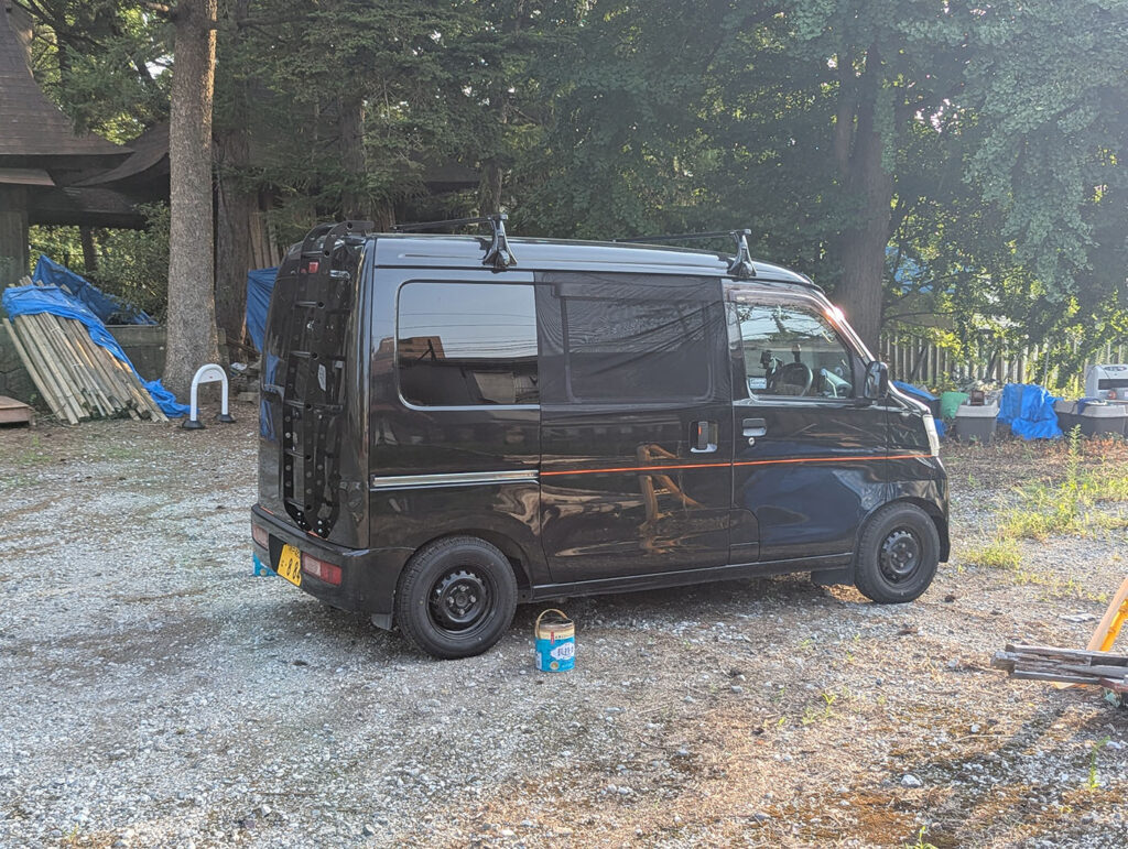 神社の境内に停められた黒い軽バンのキャンピングカー