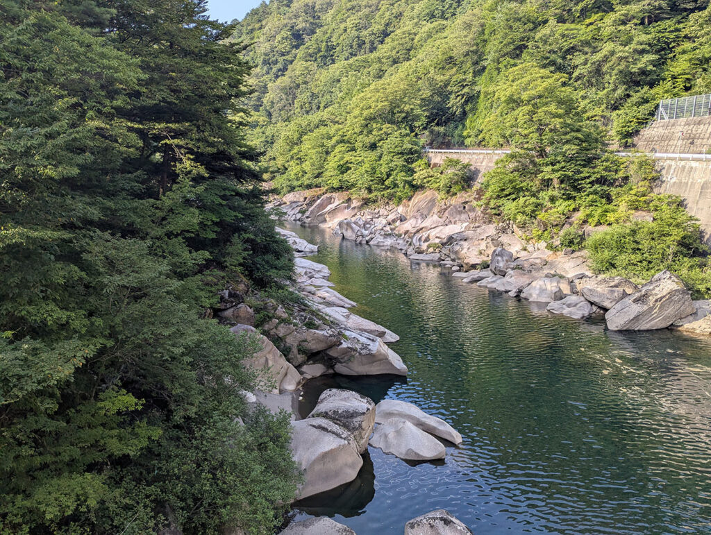 木曽の桟付近の木曽川渓谷。深緑色の清流と花崗岩の奇岩が特徴的な景観。両岸は緑豊かな森林に囲まれている。